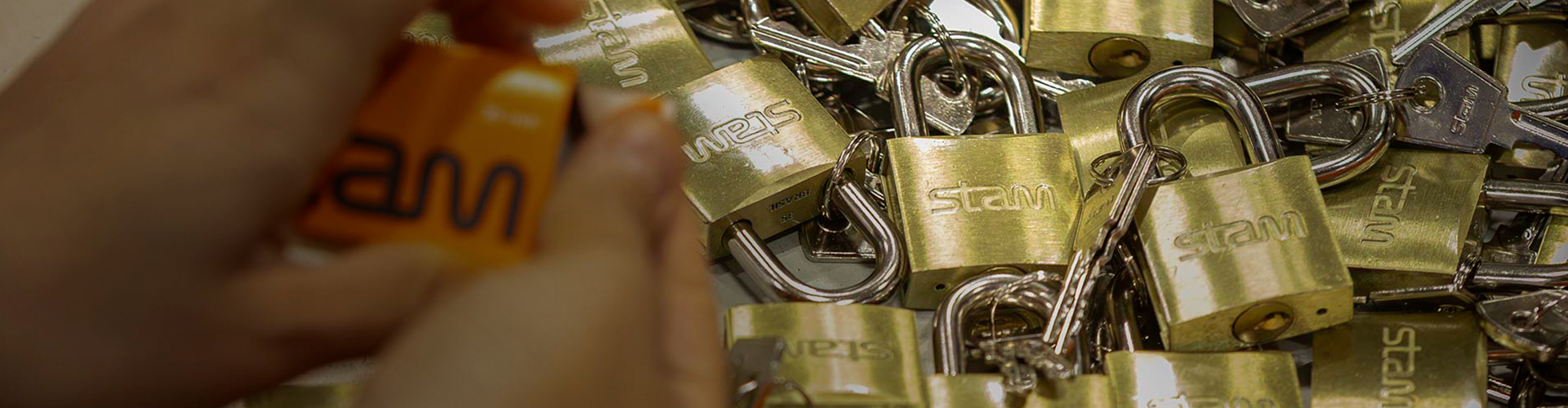 Mãos manuseiam cadeados da Stam